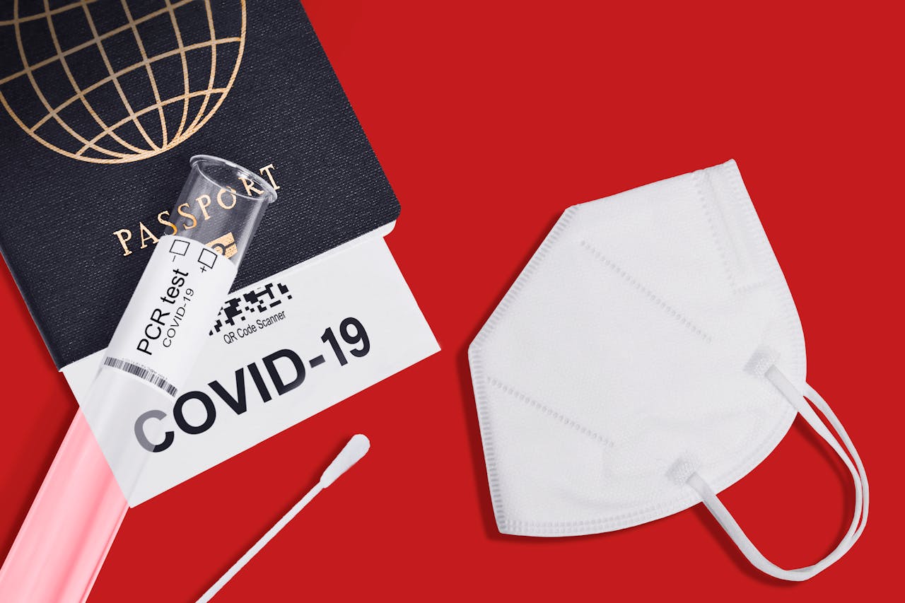 Passport, KN95 mask, and PCR test kit for COVID-19 travel preparation.