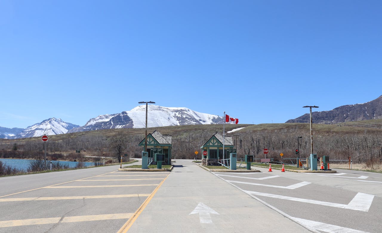 Canadian border crossing amidst stunning snow-capped mountains and clear blue sky.